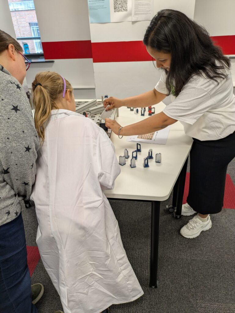 Children wearing lab coats trying to solve the laser maze.