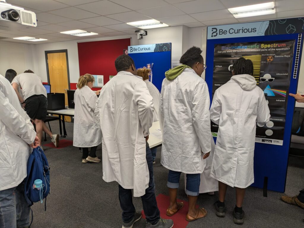 General scene of the room. Lots of people wearing lab coats engaging with our demos.